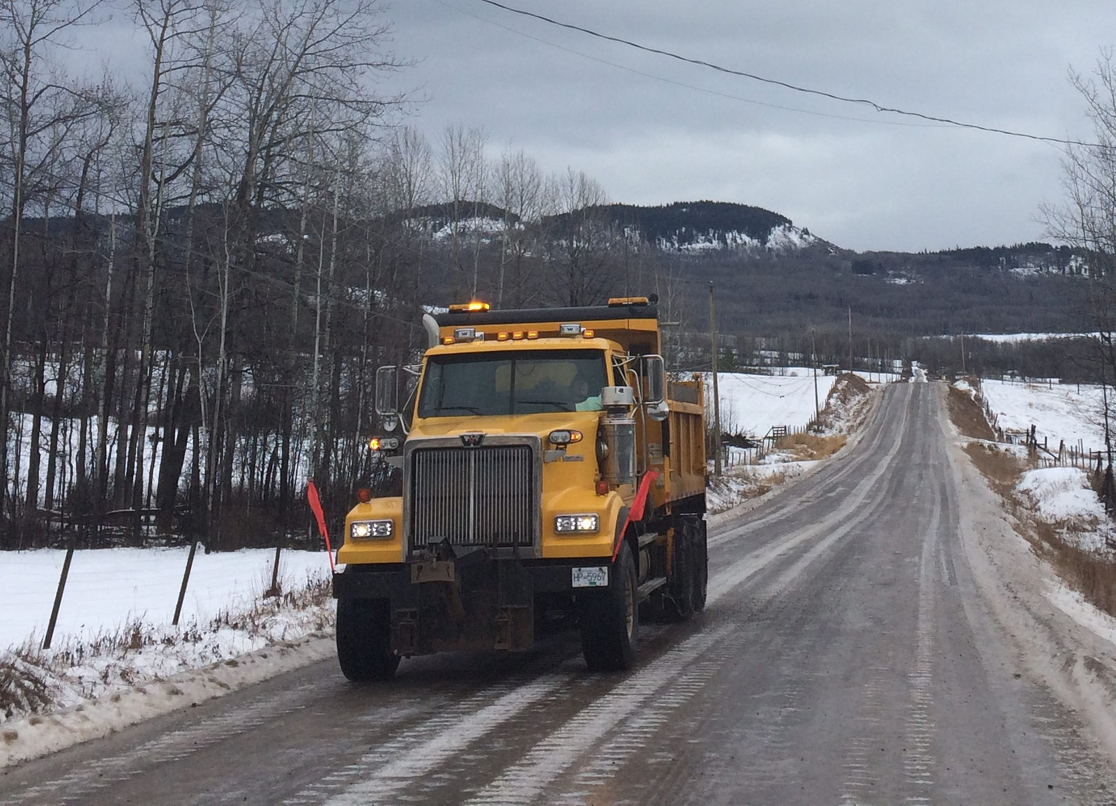 dump truck driving along wintery rural road