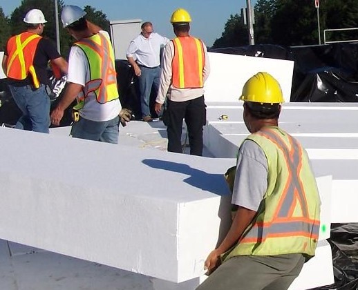 workers wearing protective gear moving large rectangle blocks of Styrofoam. 