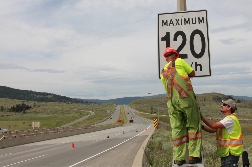 Crew installing speed limit sign on a highway