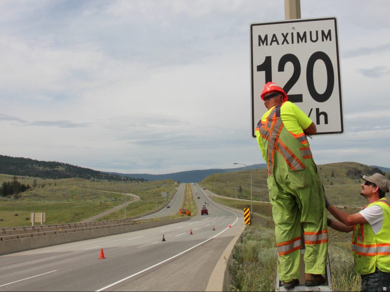 Crew installing speed limit sign on a highway