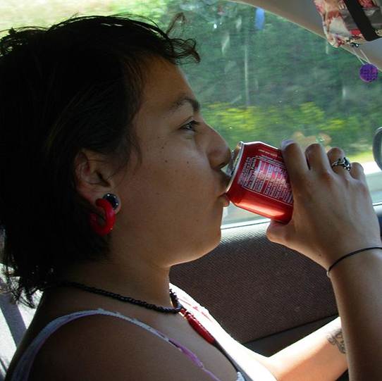 female driver drinking from a soda can while driving