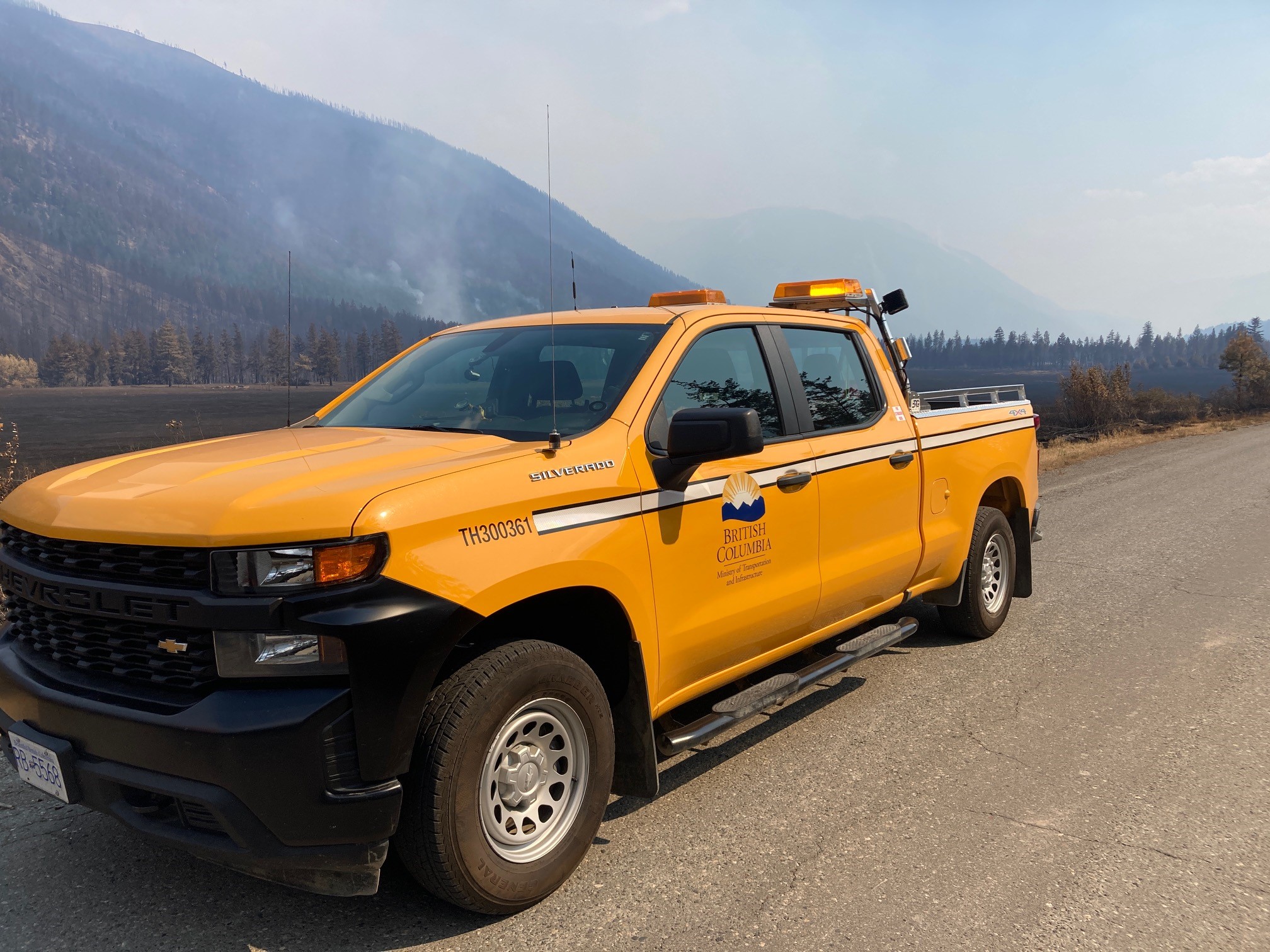 Ministry truck parked along a road near forest fire