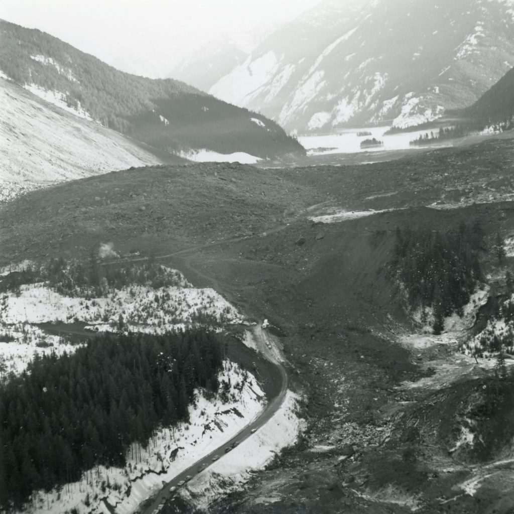 A line of cars parked along BC Highway 3 at the western edge of the slide site and the vast scope of the debris field is revealed.