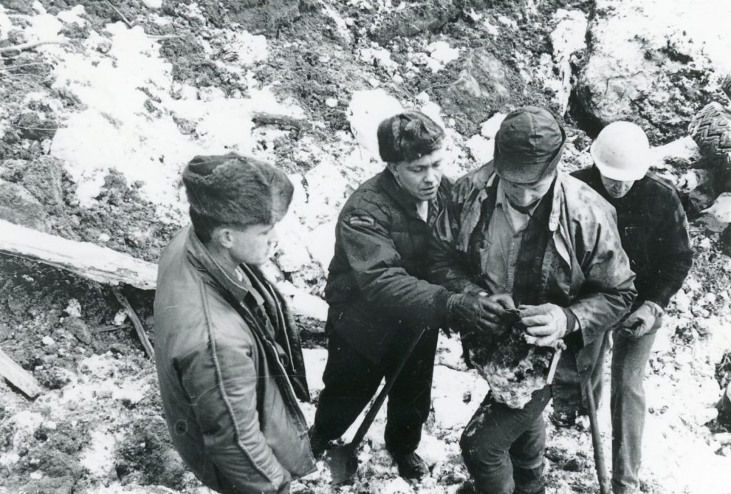 Search and rescue workers at the slide site study a recovered object.