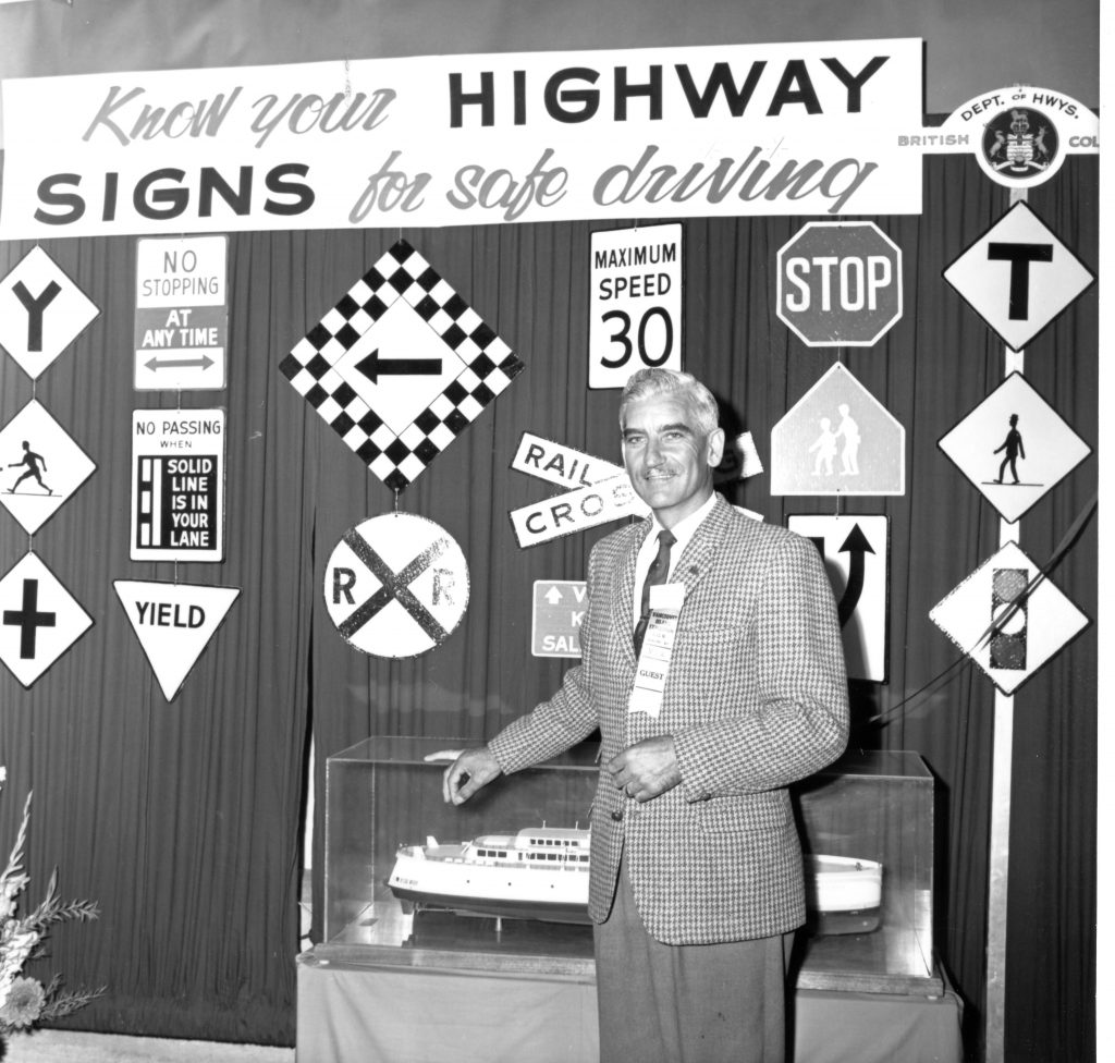 A ministry staffer stands in front of a display of highway information signs, in 1965.