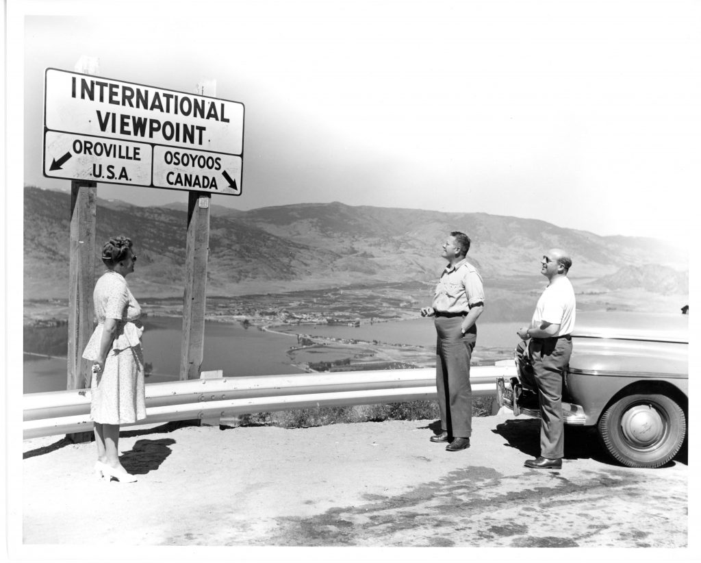 Travellers view informational signage overlooking Osoyoos.