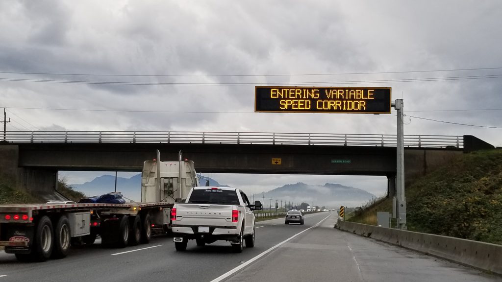 Variable speed sign with trucks driving underneath