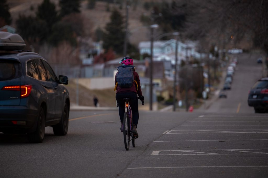 Woman cycling with car passing