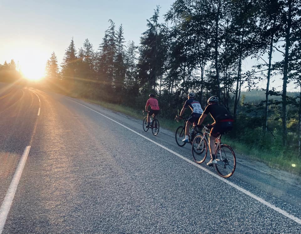 Cyclists riding on road with sun beams