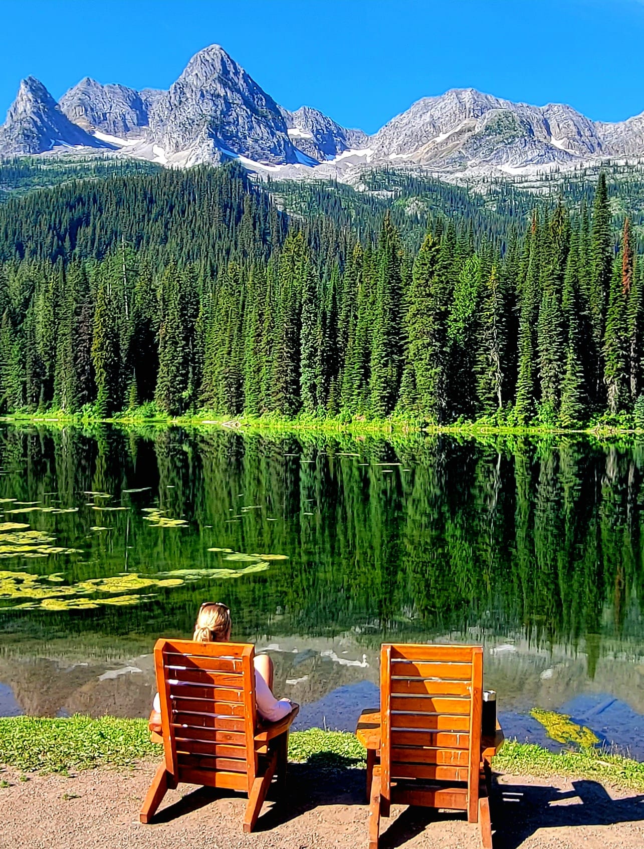 person in chair looking at water and mountains