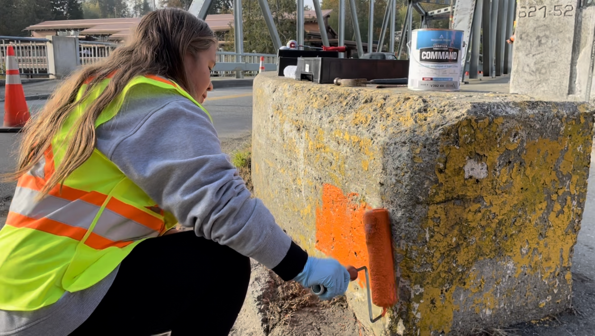 Mia Ross painting bridge barrier orange