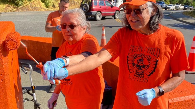 Two residential school survivors painting bridge orange